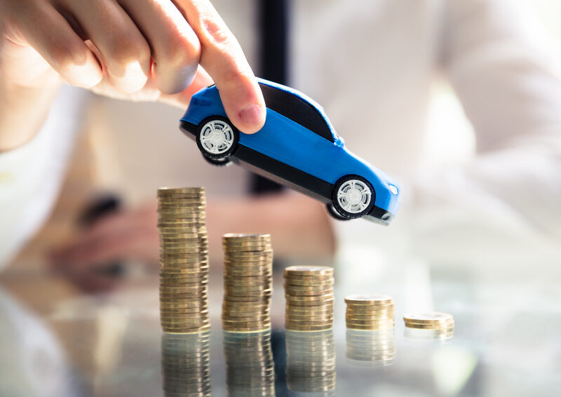 Close-up Of A Person's Hand Flying Car Over Declining Stacked Coins